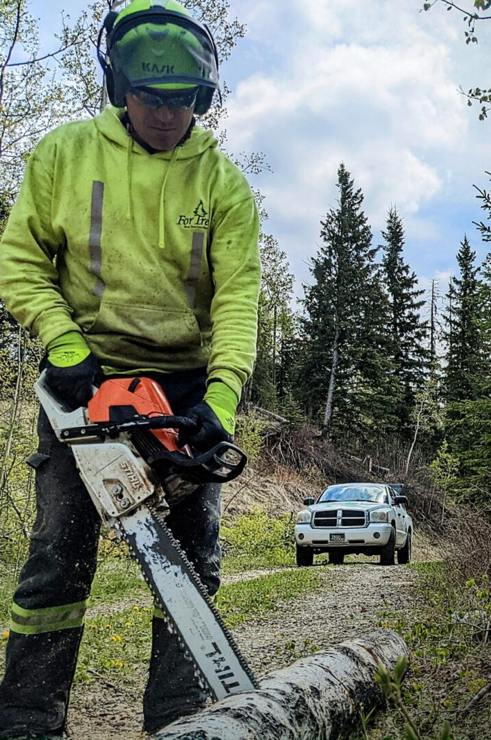 A man holding a chainsaw to cut the log
